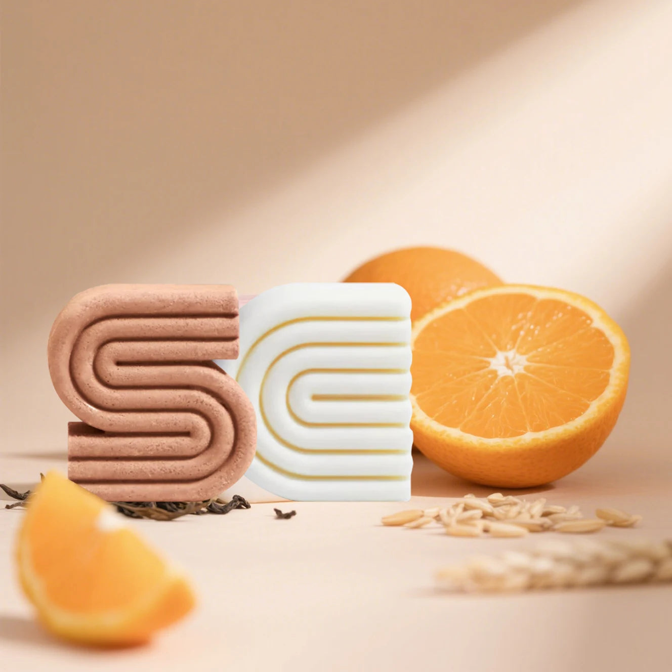 Two bars of soap with a spiral design next to oranges on a beige background